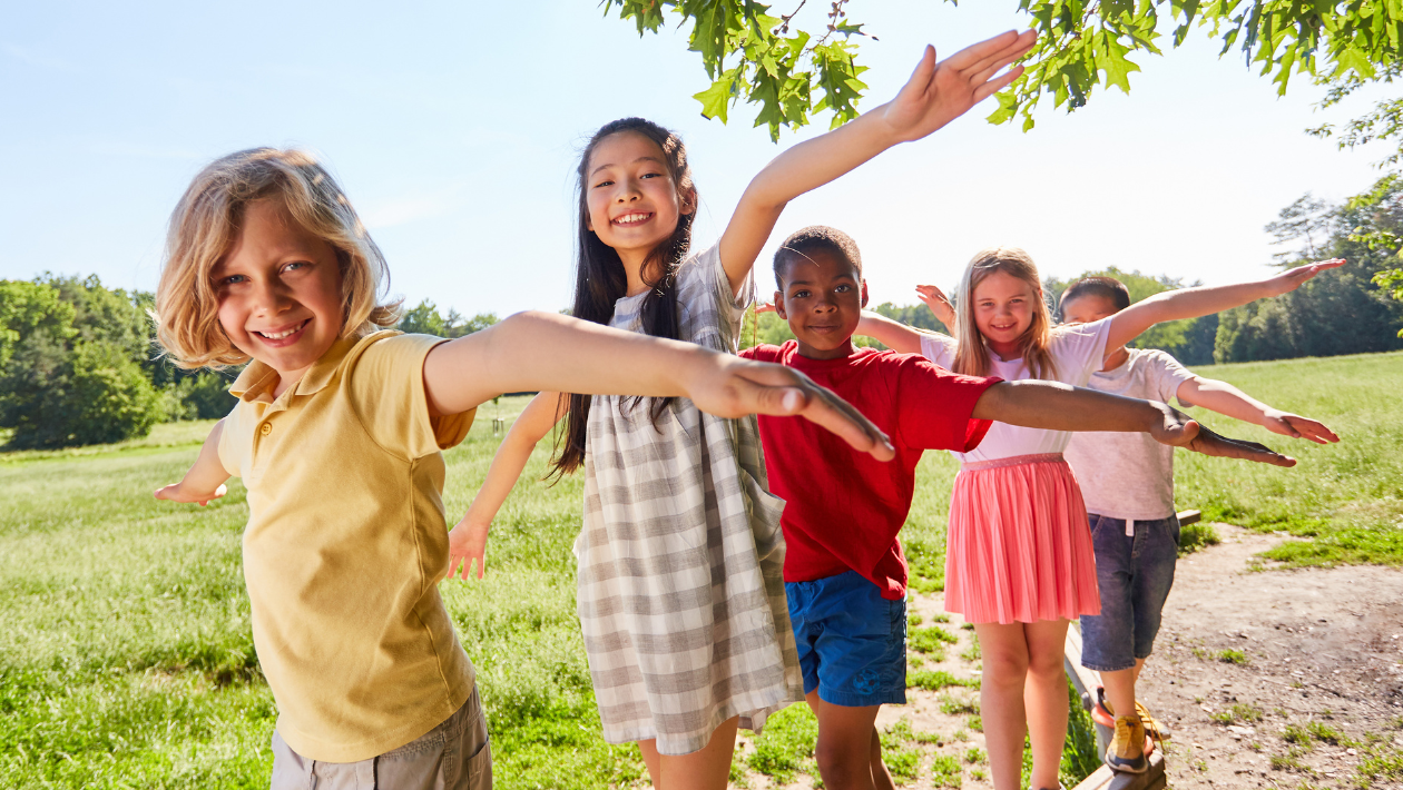 Five children with their arms out smiling for camera