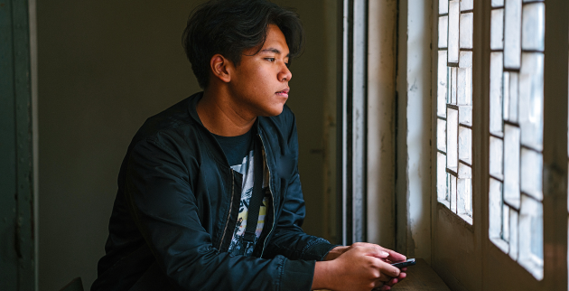 Young person stood looking out of a window