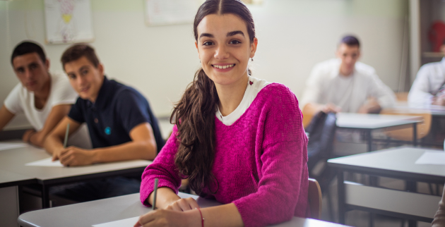 a young person sat in a classroom taking an exam. They are posing for the camera