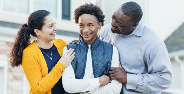 Happy young person stood with two parents