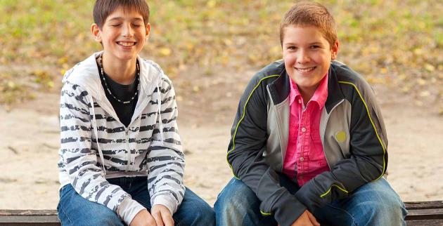 Two young men sit on a bench