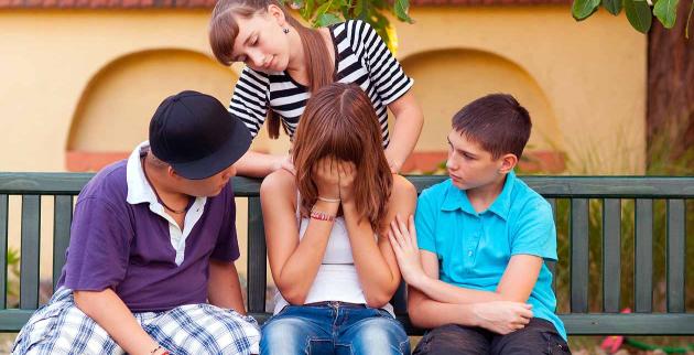 Three young people comforting a friend