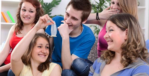 Group of young people looking at a condom