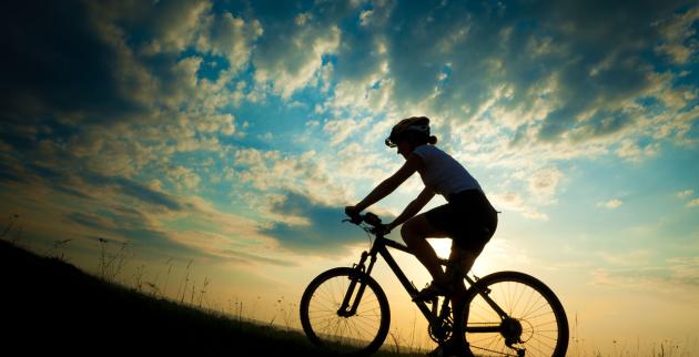A silhouette of a cyclist against a sunset
