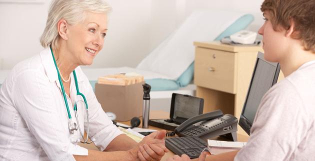 A female doctor speaks to a young male patient