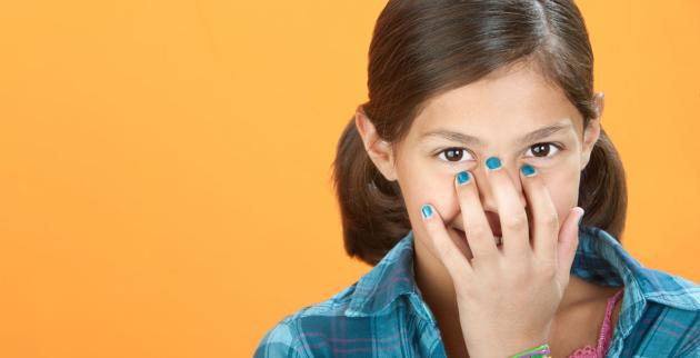 A young teenage girl hides a smile behind her hand