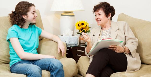 A young woman speaks to an older woman in an informal setting