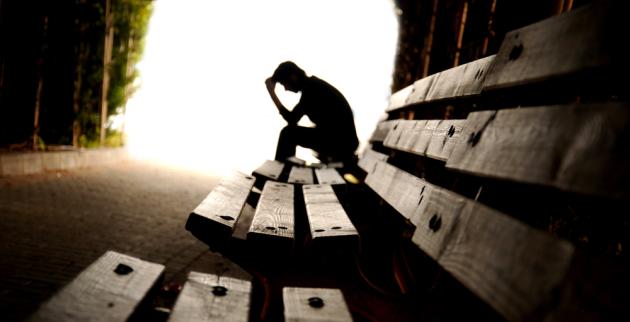 A young man sits in silhouette at the end of a tunnel