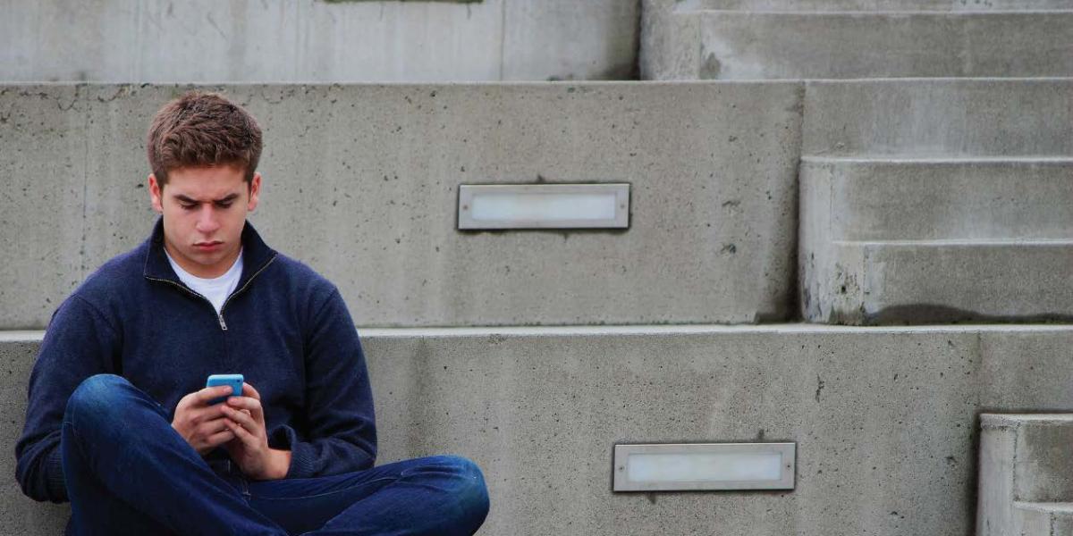 teen sat on steps using phone