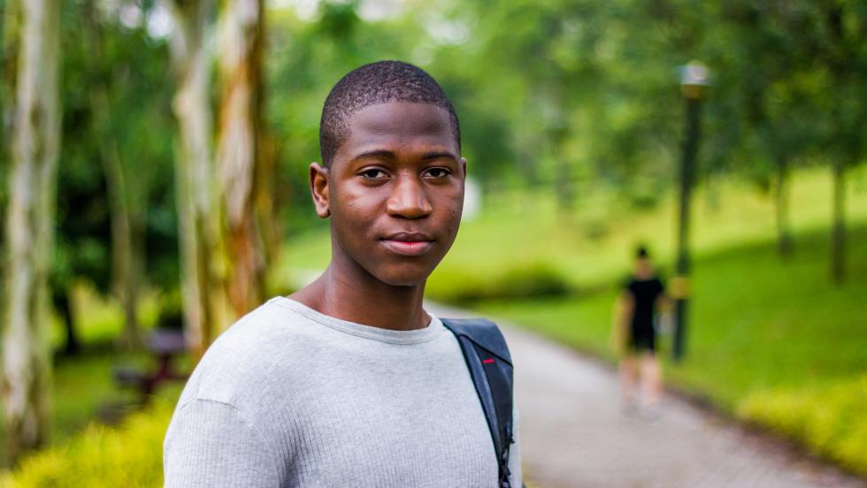 Young man in a park, looking towards camera