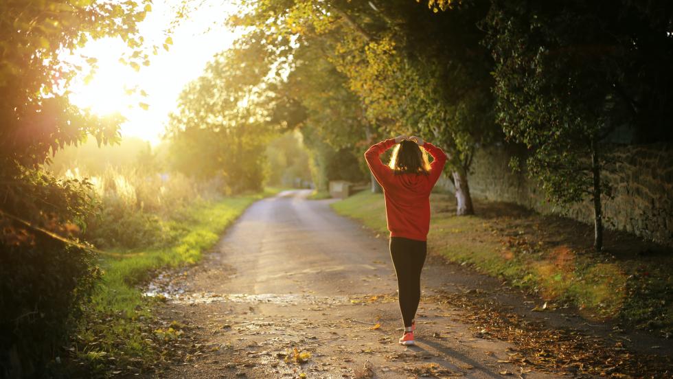 Young woman on a road, walking away from camera