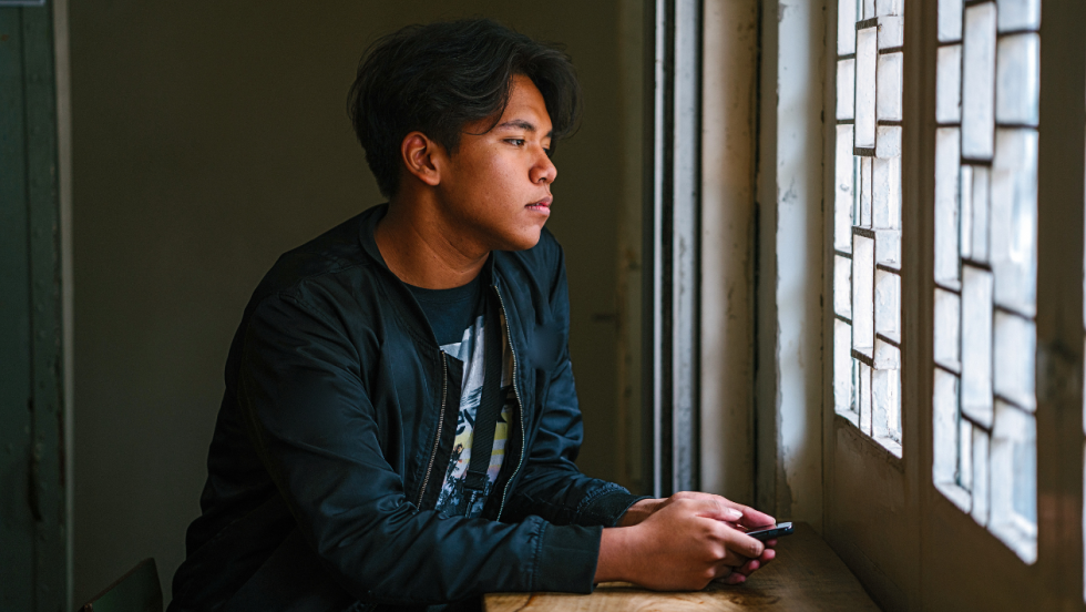 Young person stood looking out of a window