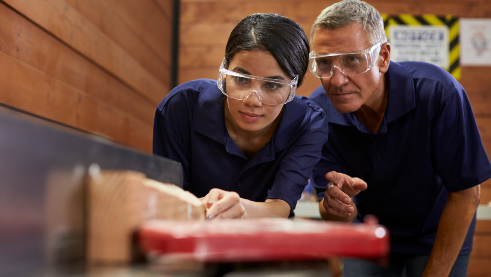 Apprentice and manager at work. They are both wearing safety goggles.