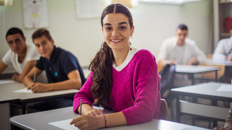 a young person sat in a classroom taking an exam. They are posing for the camera