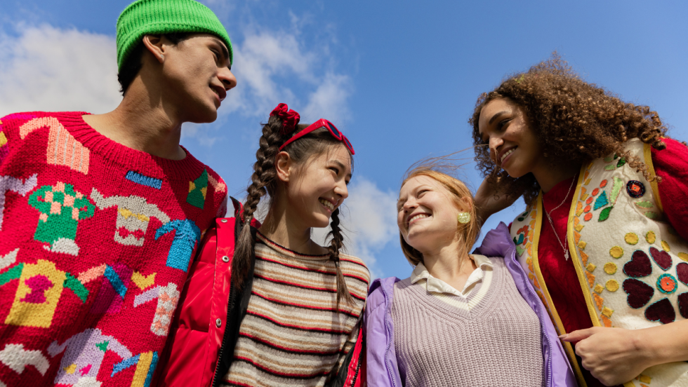 four teenage friends standing outside and laughing together