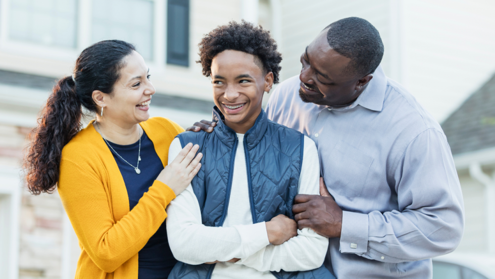 Happy young person stood with two parents