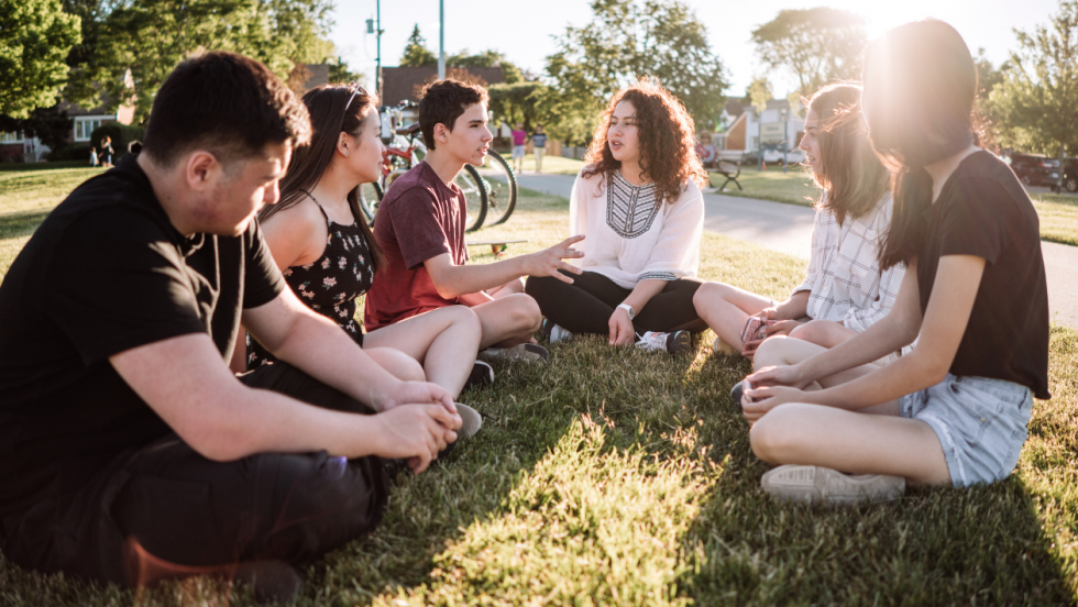 Six young people sat in a field talking