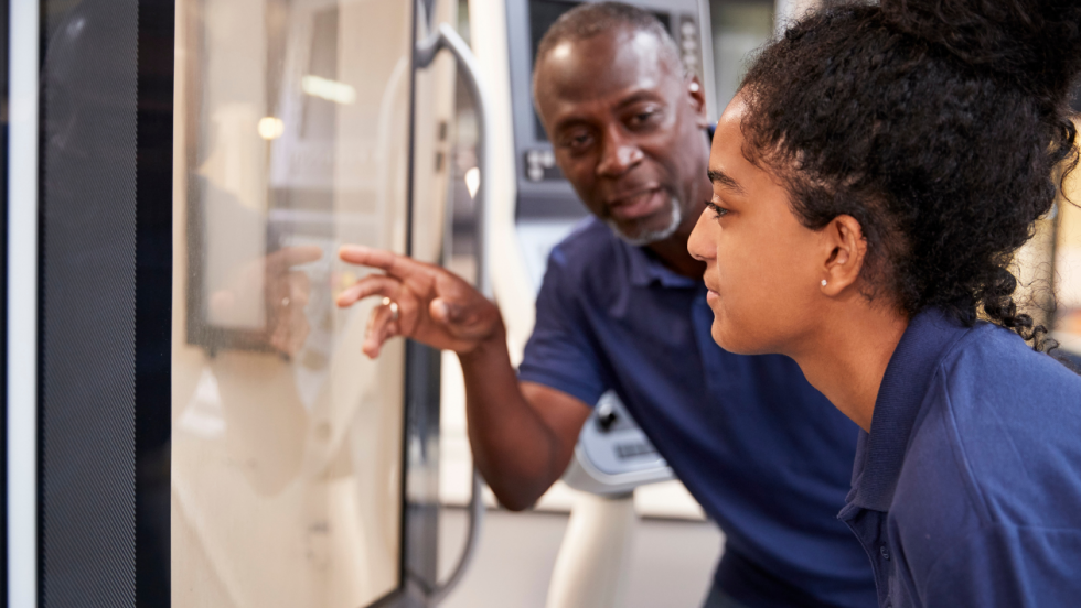 Young person being shown machinery at work by manager