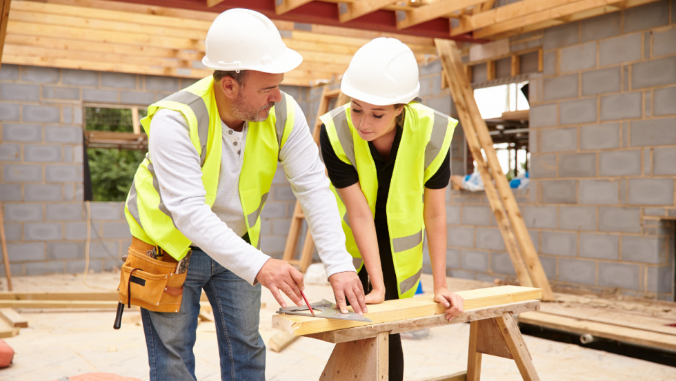 Two builders measuring wood