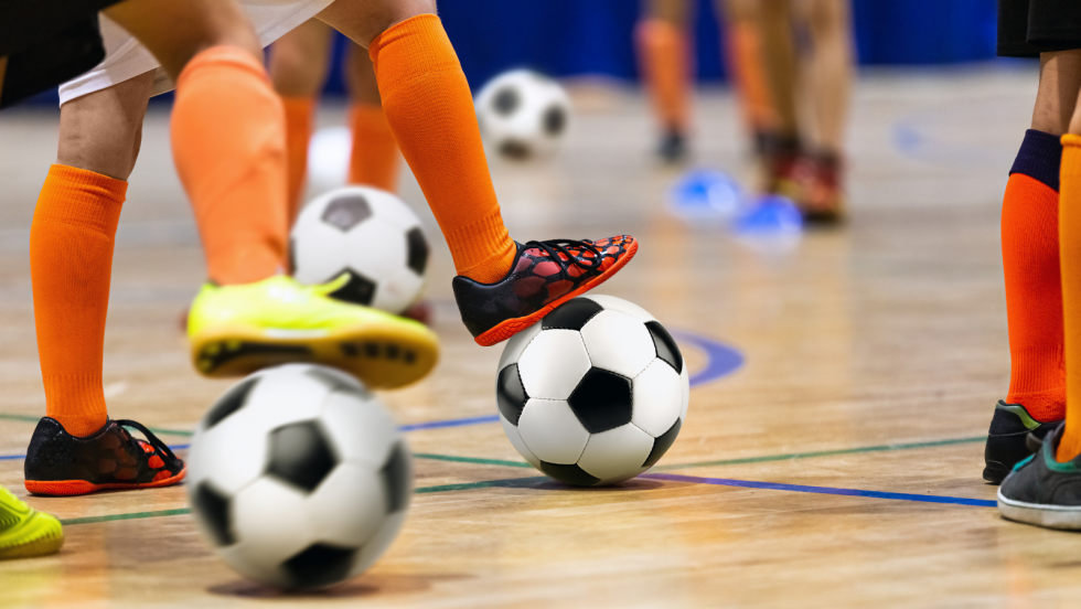 People kicking a football indoors