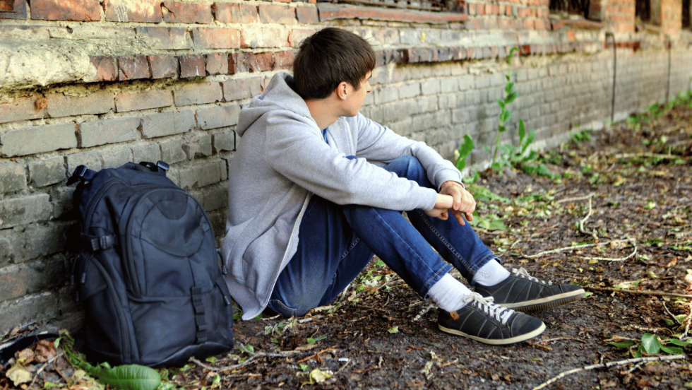 Young person sat by a wall