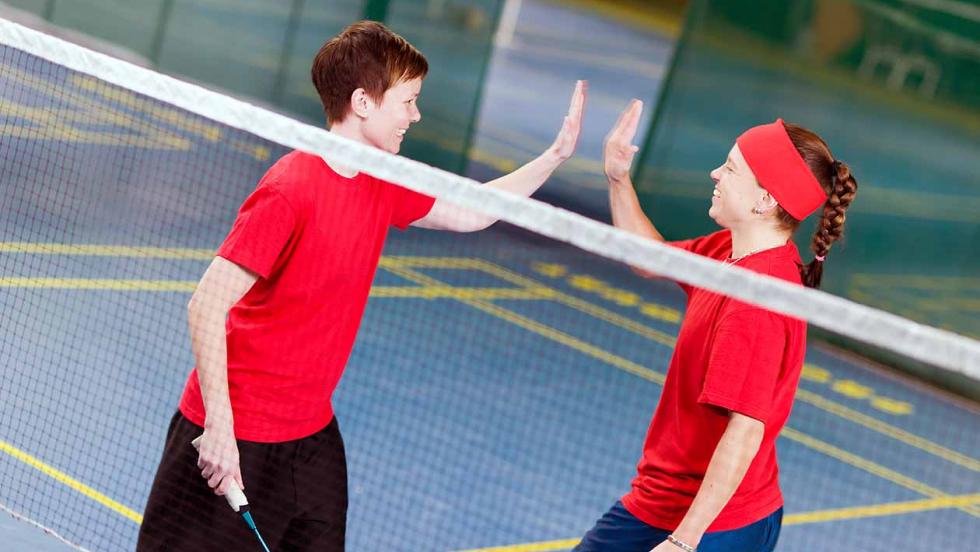 Two badminton players pause during a match and high-five