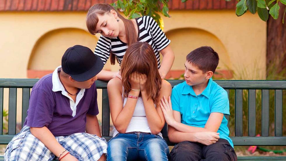 Three young people comforting a friend