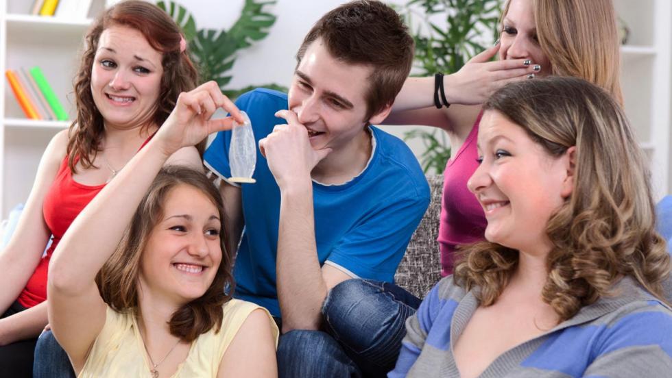 Group of young people looking at a condom