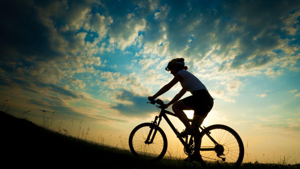 A silhouette of a cyclist against a sunset