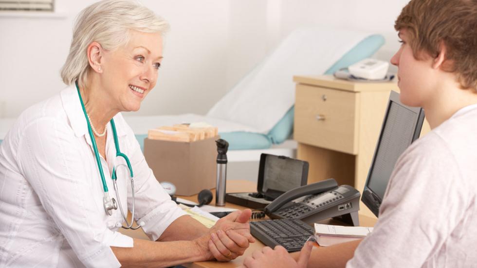 A female doctor speaks to a young male patient