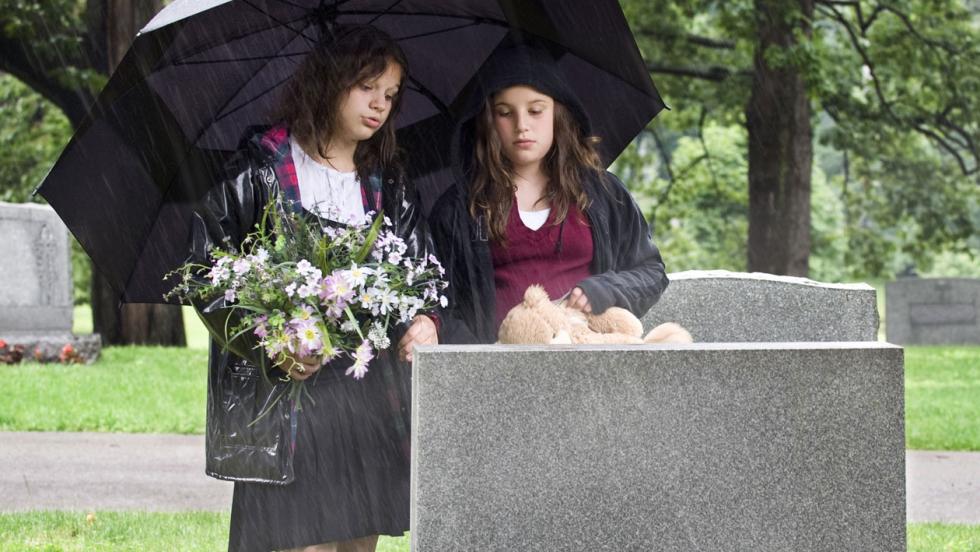 Two young women standing by a grave