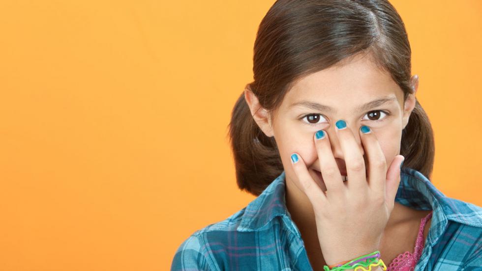 A young teenage girl hides a smile behind her hand