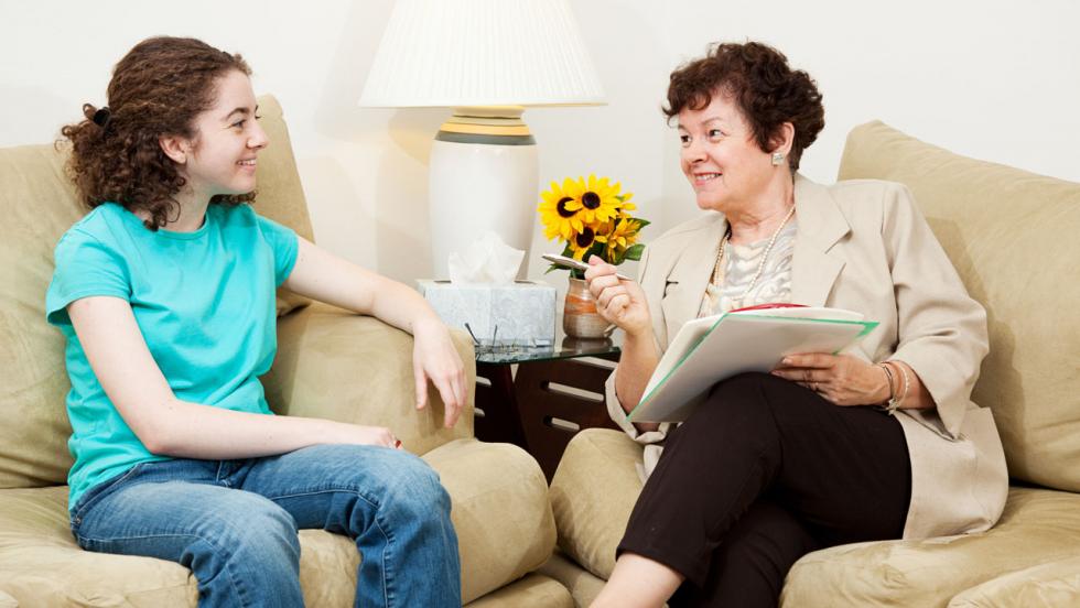 A young woman speaks to an older woman in an informal setting