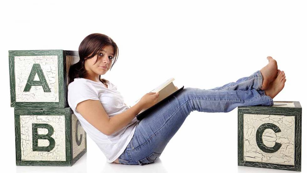 Young woman reading among alphabet blocks