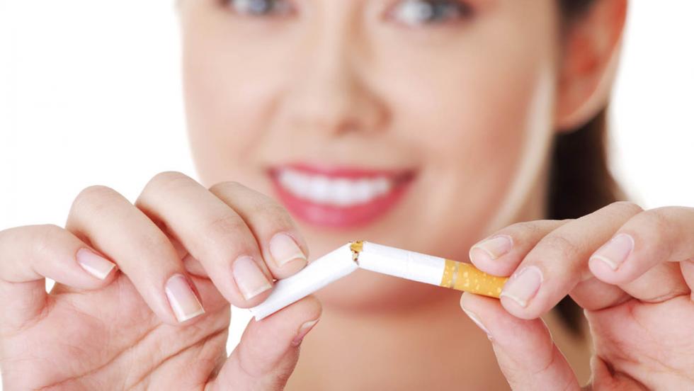 Smiling woman snapping a cigarette in two