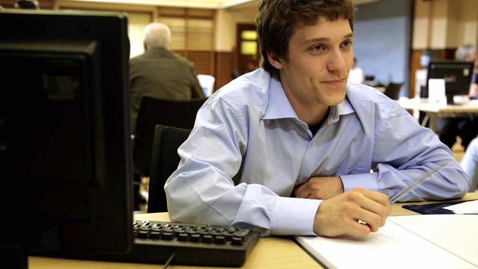 Young man, smiling while working at a desk.