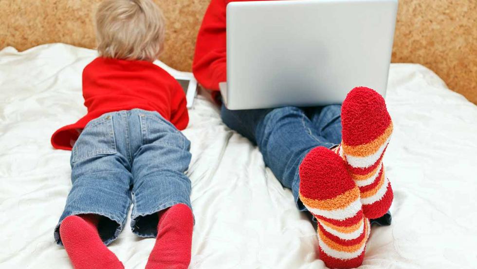 Two young people using a lap-top and a tablet to browse websites