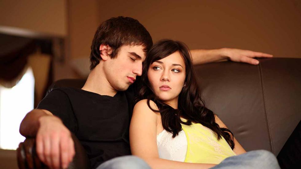A young man puts his arm around a young woman who is looking uncertain