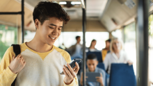 young person stood on a bus looking at phone