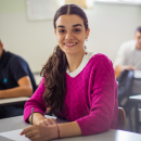 a young person sat in a classroom taking an exam. They are posing for the camera