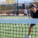 young person playing tennis outside