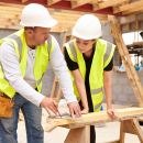 Two builders measuring wood