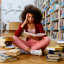 Stressed student sat in library with two piles of books