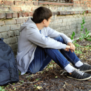 Young person sat by a wall