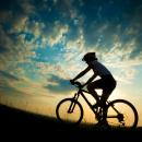 A silhouette of a cyclist against a sunset