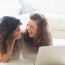 Two girls sharing a laptop and laughing