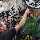 A Young Man sprays graffiti onto a wall